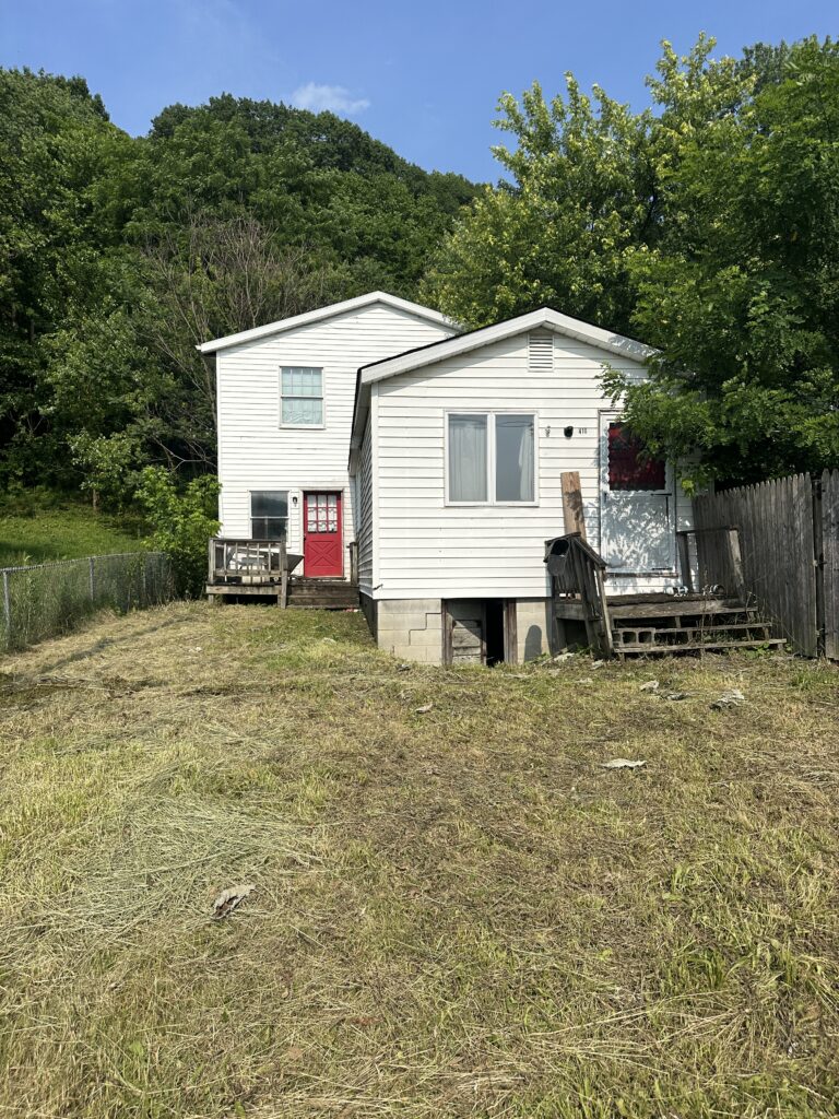 Front view of single-family detached home at 408 & 410 3rd Avenue, Beaver Falls PA, white siding with red doors, Eastvale neighborhood, ready for investor or homebuyer.